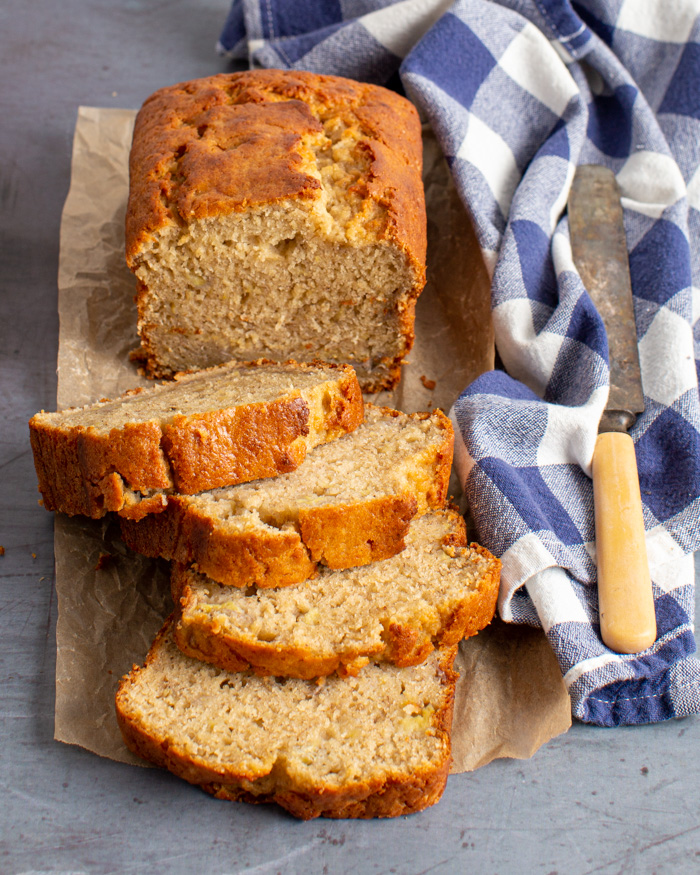 loaf of banana bread on parchment paper with 4 slices cut out